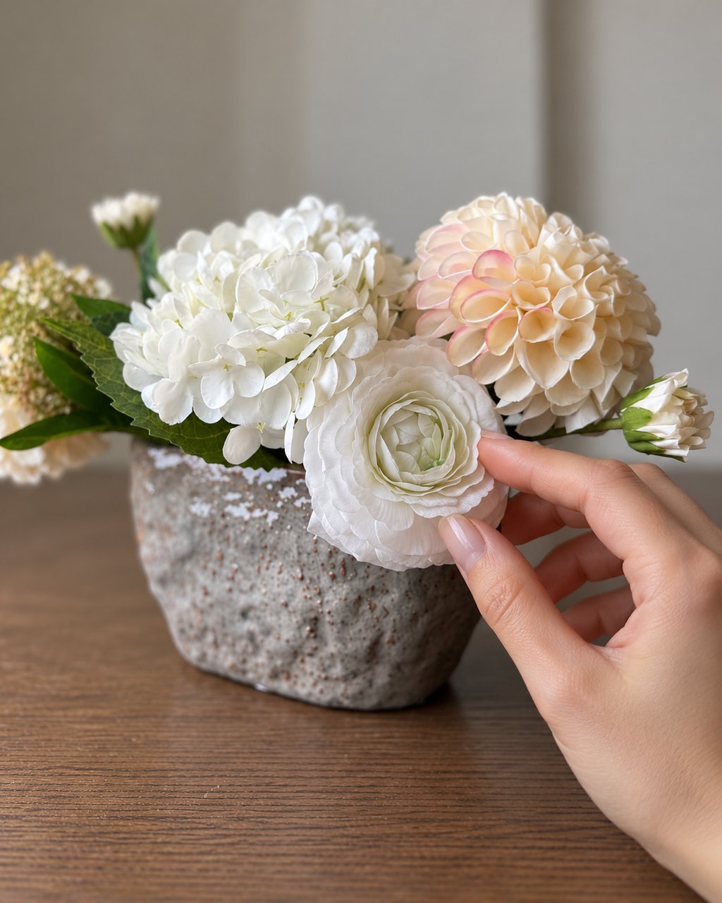 A hand touching the real-touch petals of an arrangement